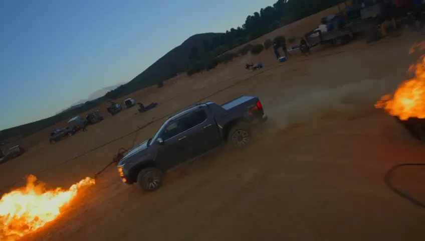 Bakkie racing past a wall of fire on a stunt set