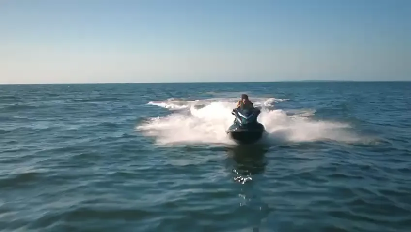 Jet-ski throwing spray, chased at sea level